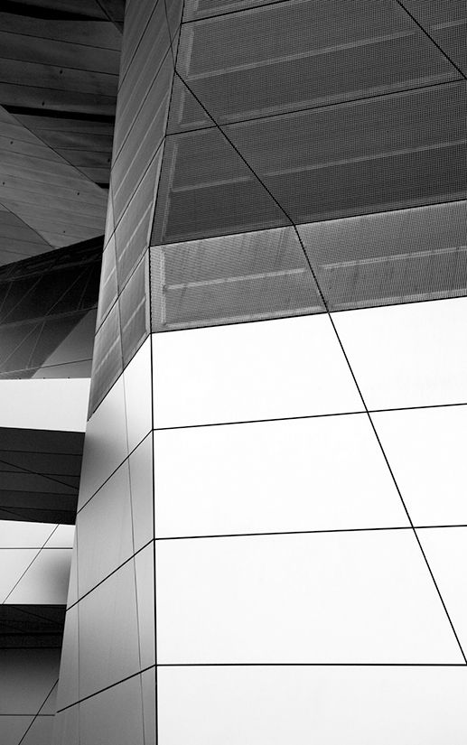 Close up black and white photo of the exterior of a glass building.