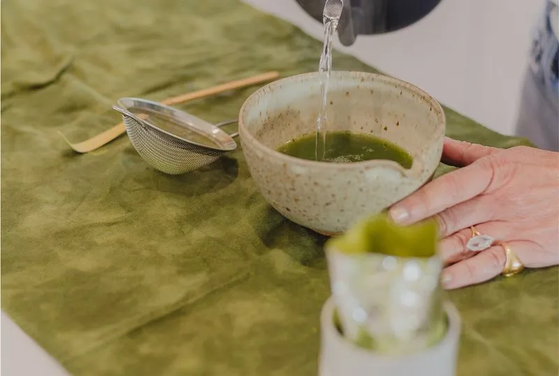 An image of a woman making matcha at a kitchen counter