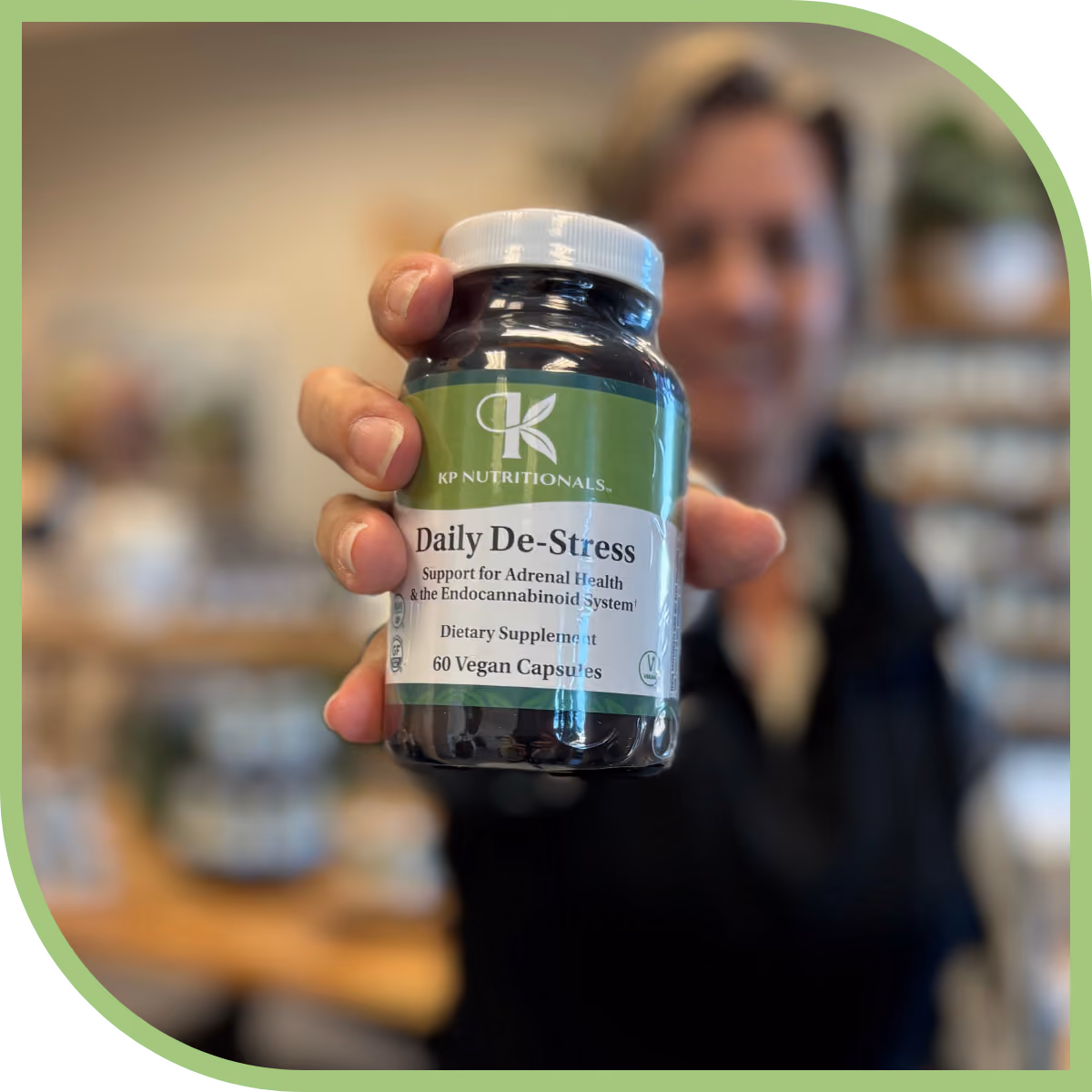 Person holding a bottle of KP Nutritionals Daily De-Stress vegan dietary supplement capsules.