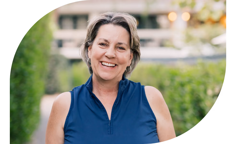 Smiling woman named Kimberly Potter with short hair wearing a blue sleeveless top outdoors with blurred greenery.