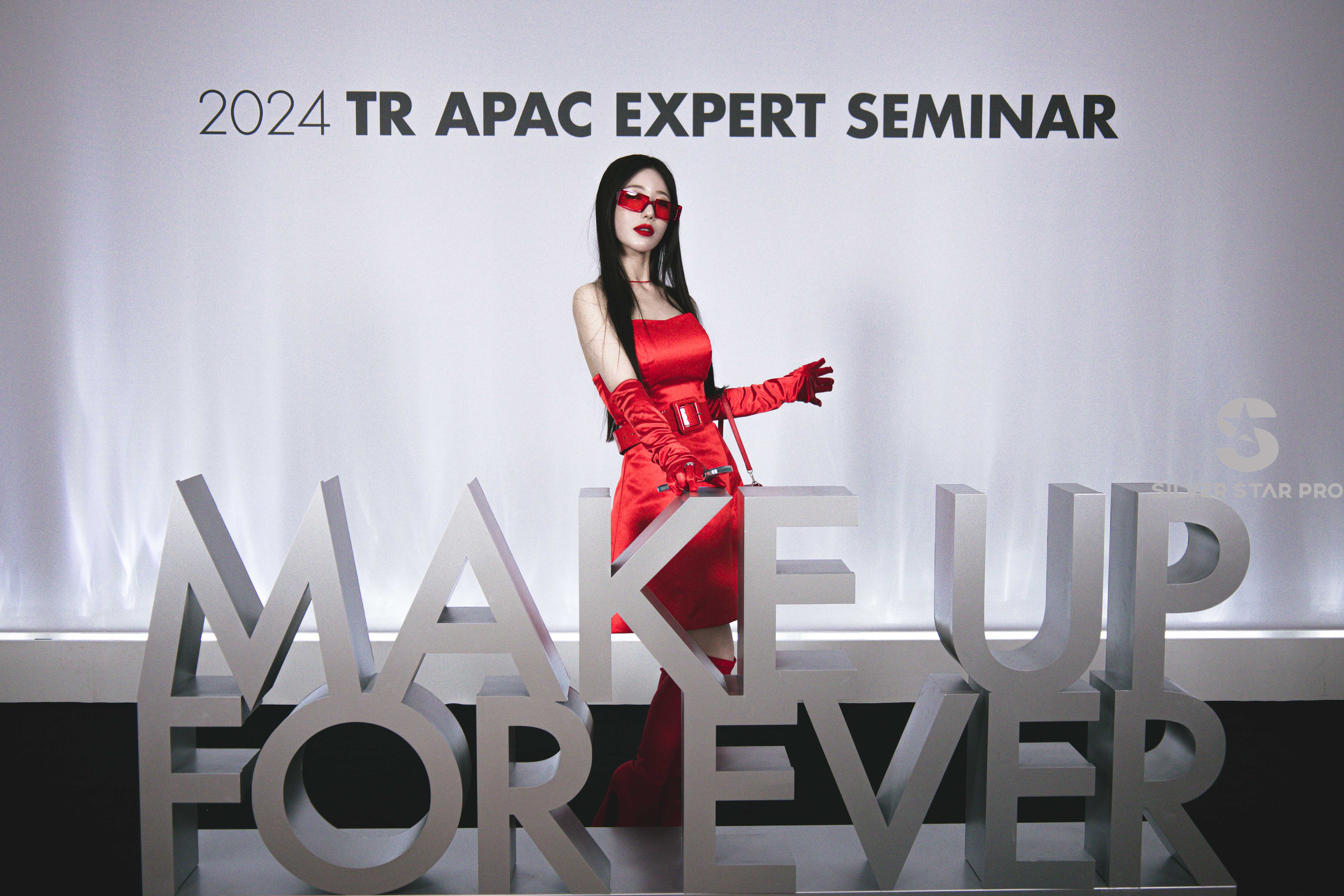 A photo of a stylish guest in a red outfit posing at the 2024 TR APAC Expert Seminar for MAKE UP FOR EVER, captured by Silver Star Pro — showcasing premium event photography and videography in Dubai with elegant branding and lighting.