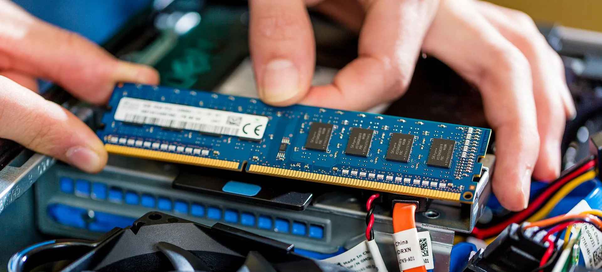 Hands inserting a memory module into a computer mainboard