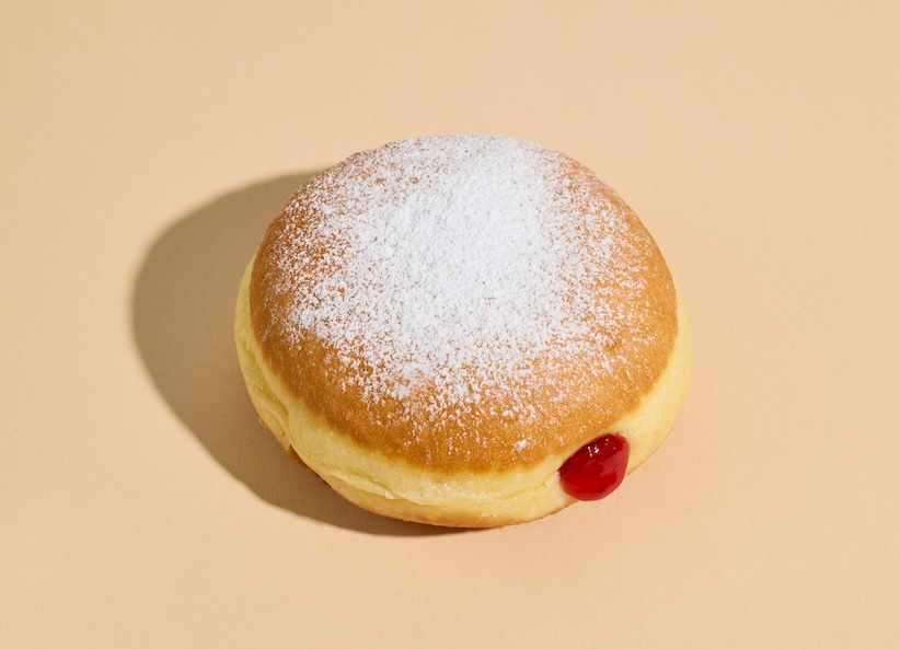 Marmeladenkrapfen mit Staubzucker auf beigem Hintergrund