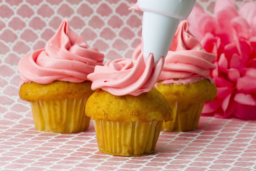 Spritzbeutel verziert Cupcakes mit rosa Cremetupfen