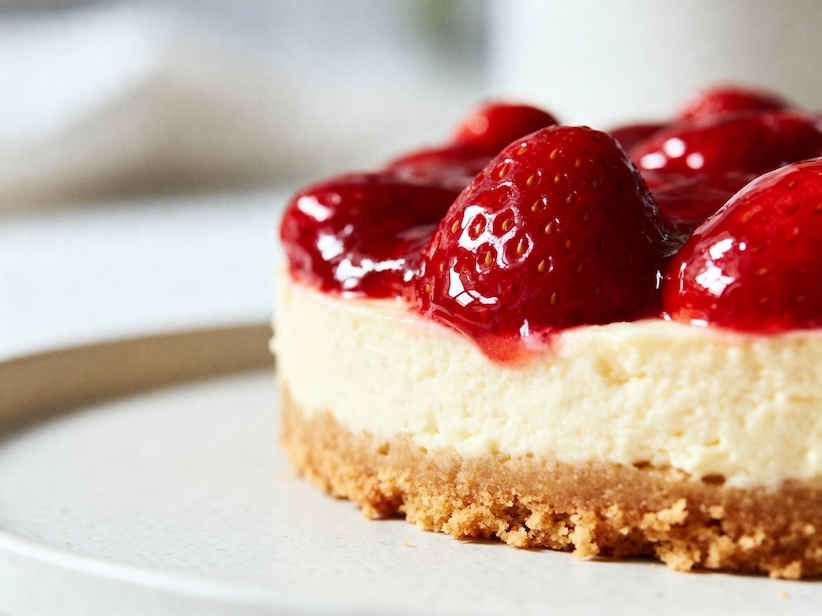 Nahaufnahme einer Erdbeer-Käsetorte mit glasierten Erdbeeren auf Keksboden