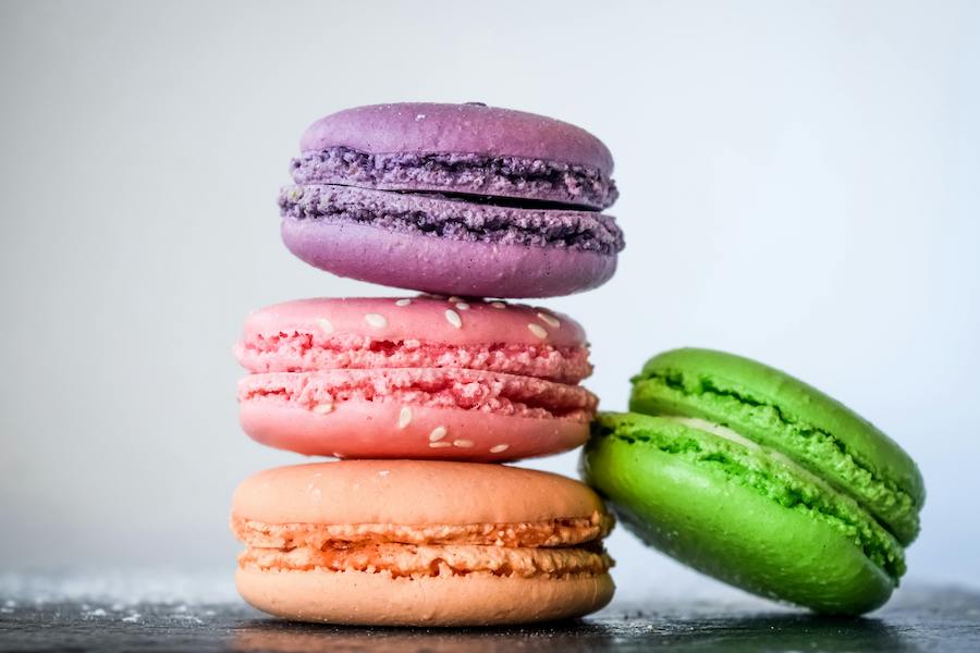 Stapel violetter, rosa, oranger und grüner Macarons auf hellem Hintergrund