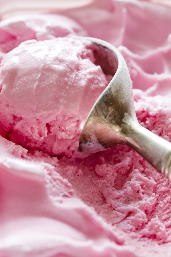 Nahaufnahme eines Metall-Portionierers mit einer Kugel rosa Erdbeereis