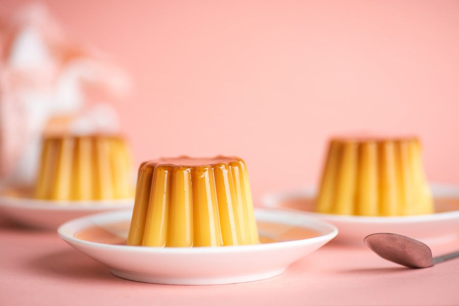 Karamellpuddings auf kleinen Tellern vor rosa Hintergrund