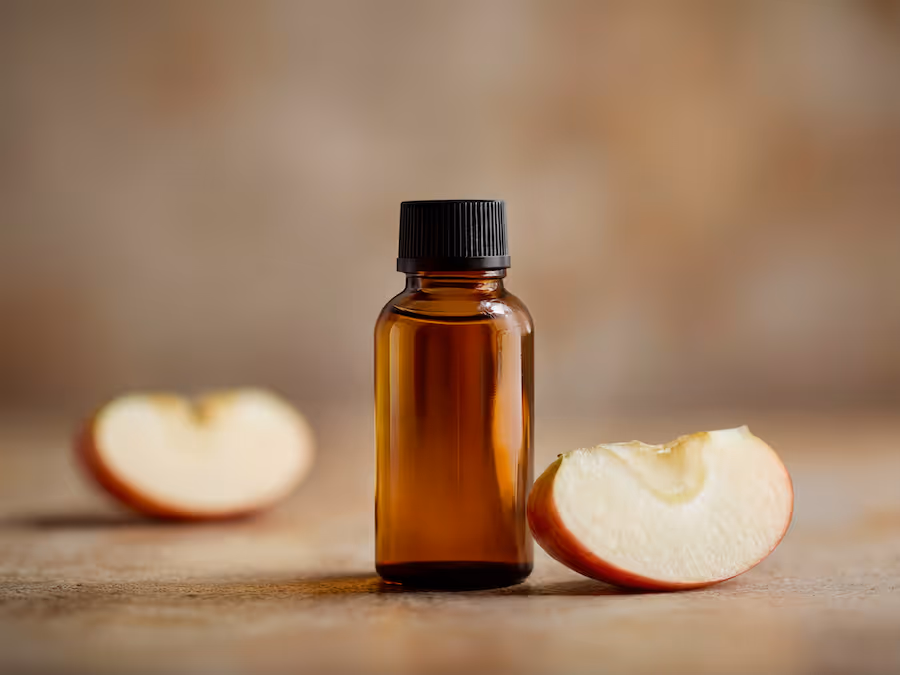 Kleine Braunglasflasche mit Apfelaroma zwischen zwei Apfelspalten