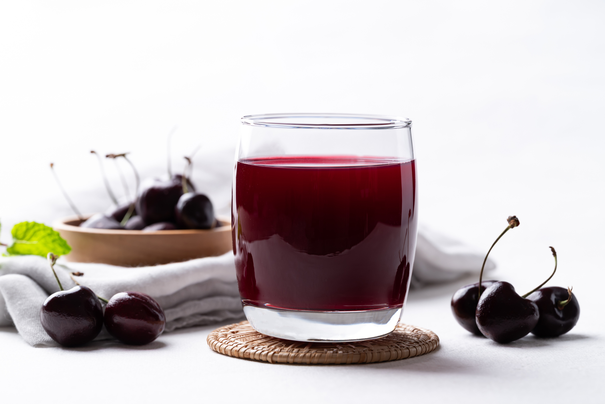 Glas Sauerkirschsaft mit frischen Kirschen auf einem weißen Tisch