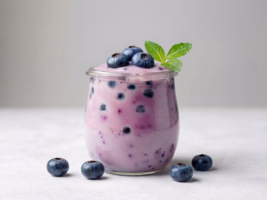 Glas Heidelbeerjoghurt mit frischen Heidelbeeren und einem Minzblatt