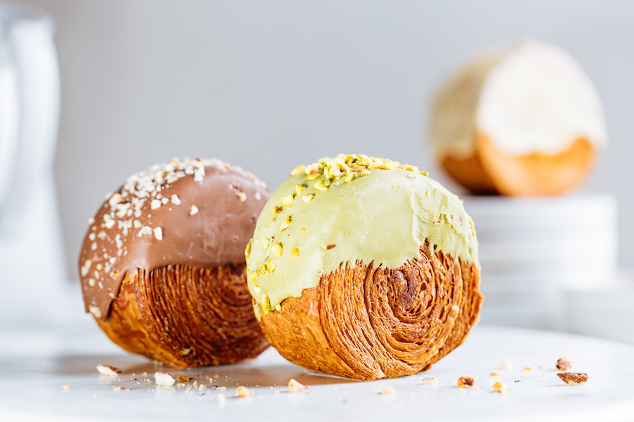 Zwei runde Blätterteiggebäcke, eines mit Milchschokolade und Nüssen, eines mit Pistaziencreme glasiert