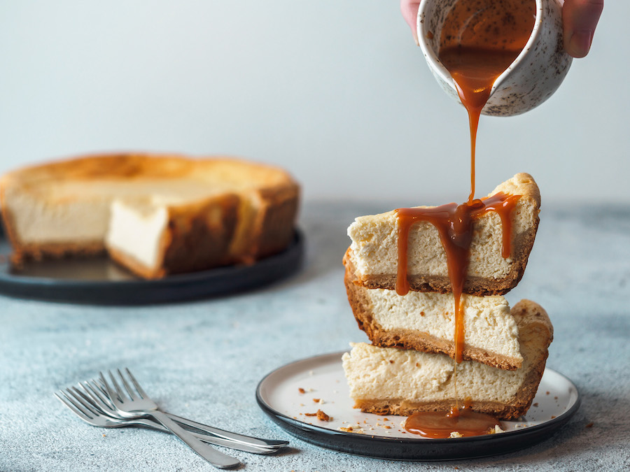 Karamellsauce wird über gestapelte Stücke Cheesecake gegossen