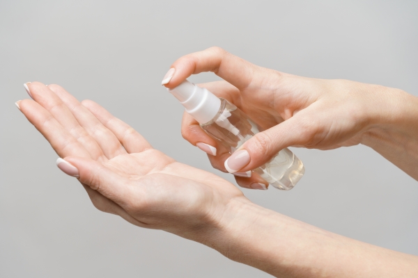 Hände sprühen Desinfektionsmittel aus einer kleinen Pumpflasche