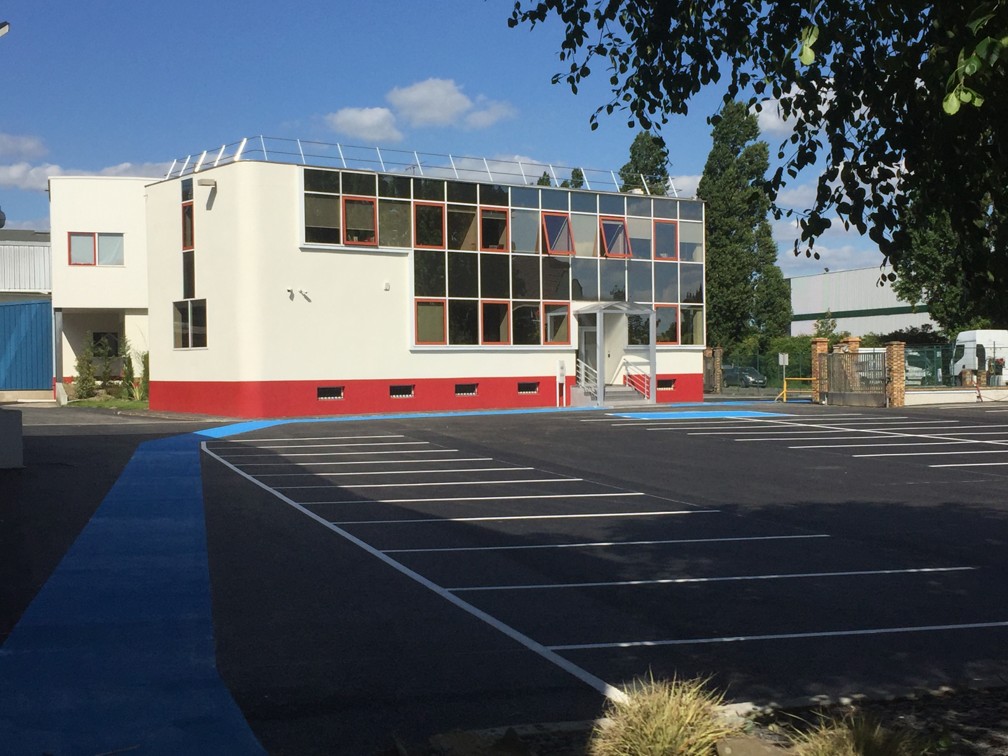 Office building of the AGRANA Fruit site in France with red base and freshly marked car park