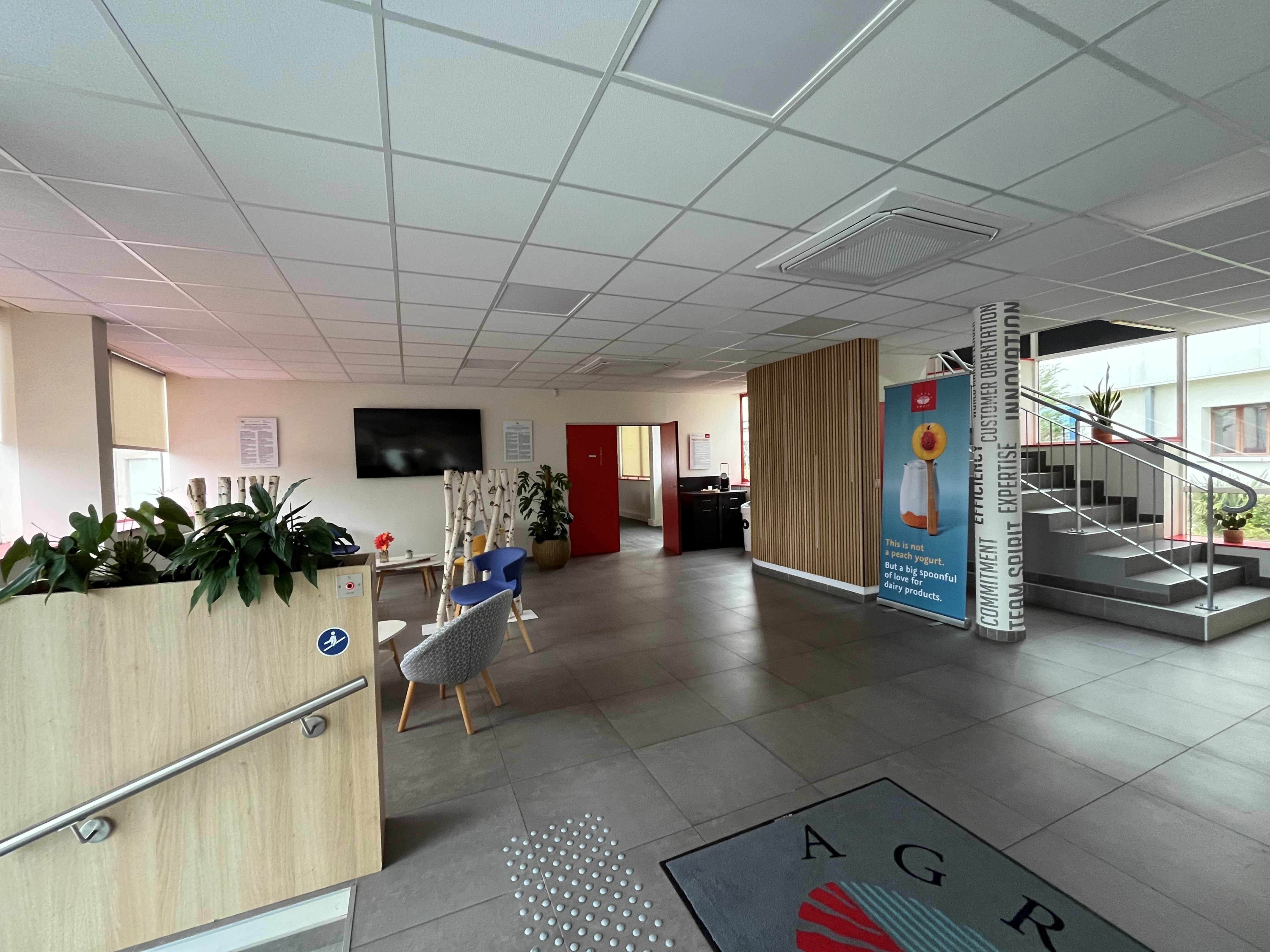 Reception area of the AGRANA Fruit site in France with seating, plants and an AGRANA floor mat