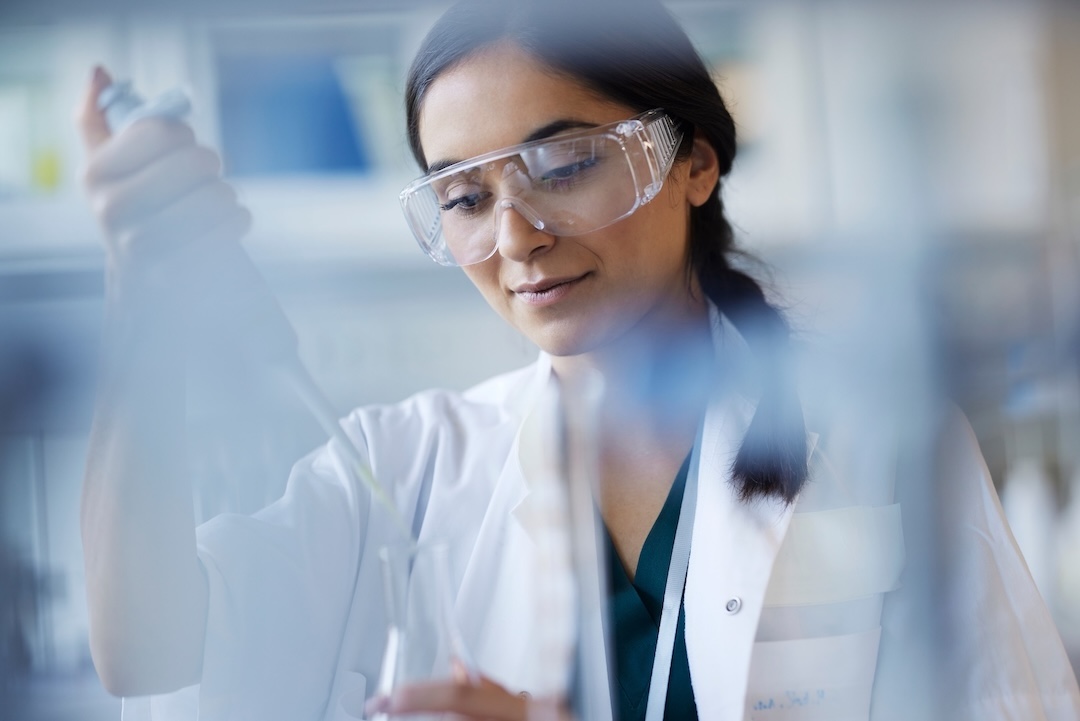 Scientist in a lab coat and safety glasses pipetting in a laboratory [no AI]