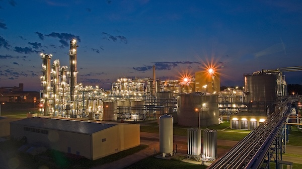 Industrial plant with illuminated process columns and tanks at dusk [no AI]