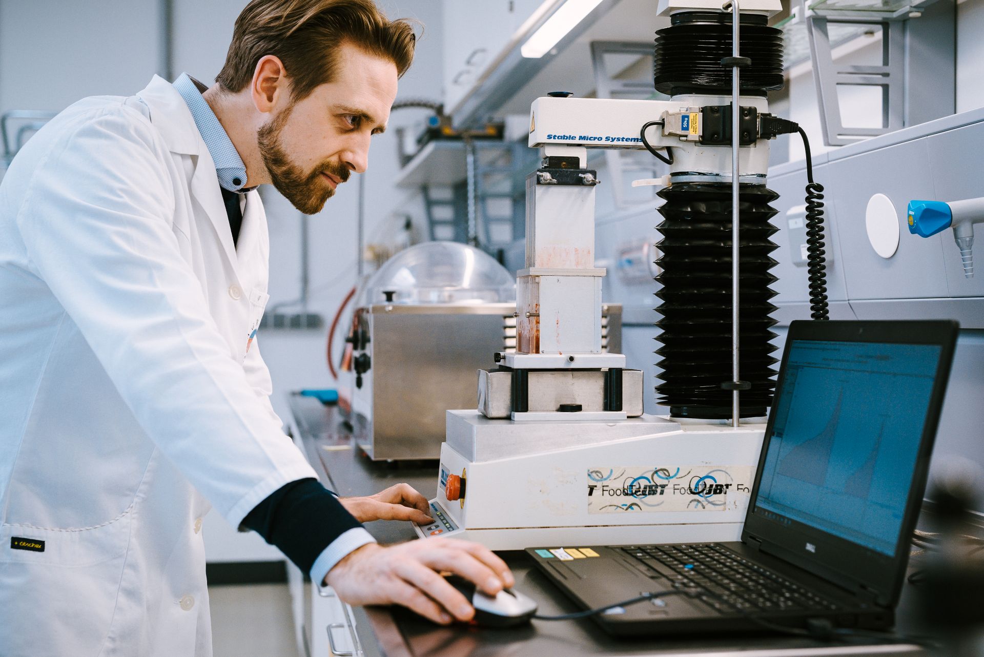 Forscher im Laborkittel bedient einen Texture Analyser und Laptop im ARIC