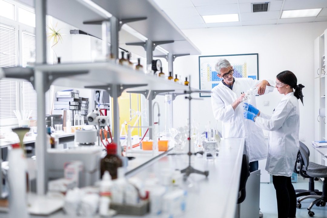 Zwei Forschende in Laborkitteln arbeiten gemeinsam an einem Labortisch in einem hellen Labor [no AI]