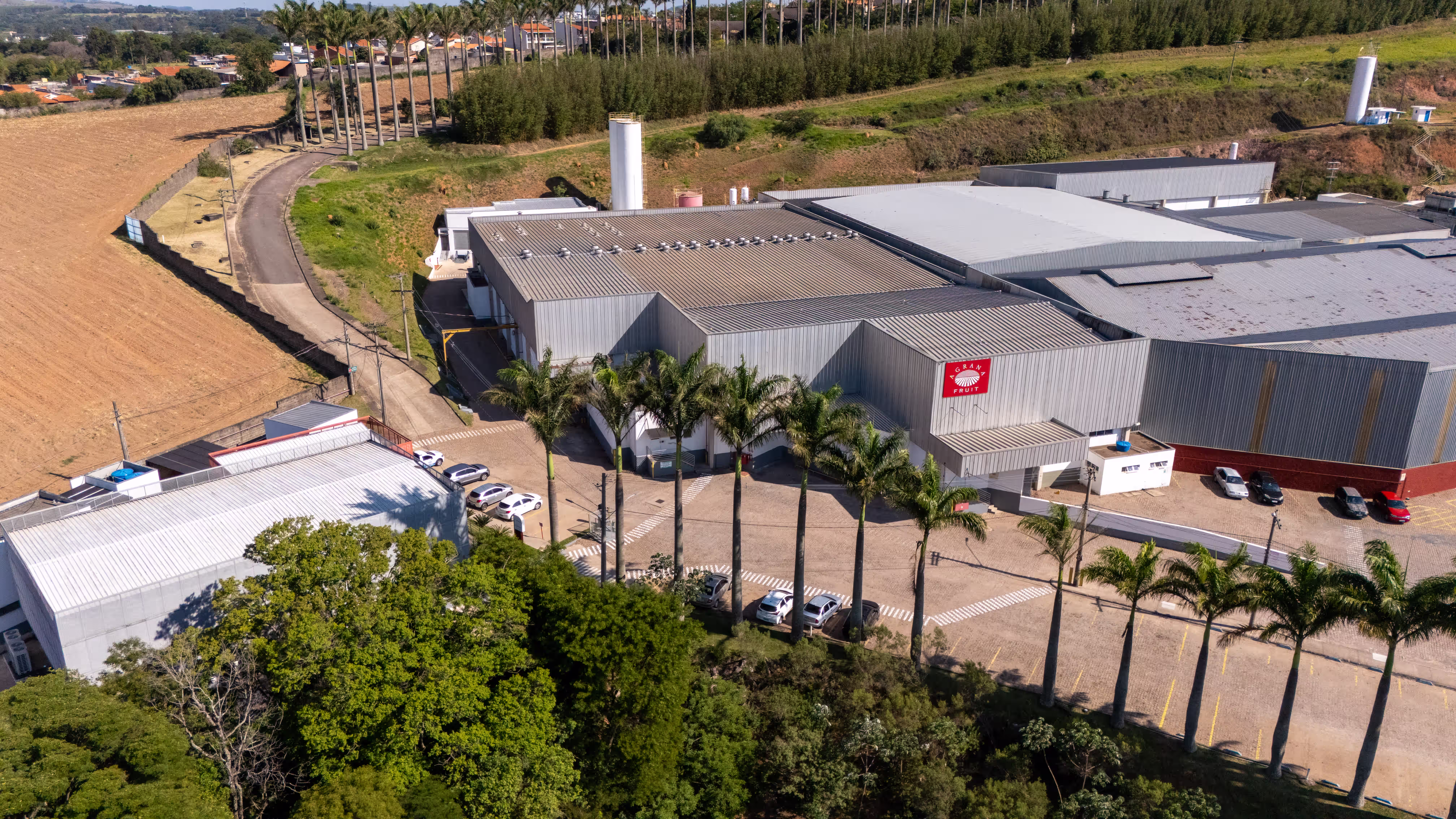 AGRANA Fruit plant in Brazil seen from above, with palm-lined driveway and fields behind [no AI]
