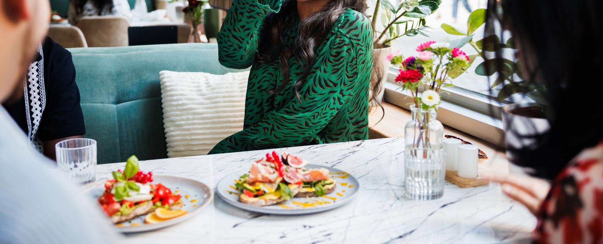People sharing plates of food at a restaurant table with flowers [no AI]