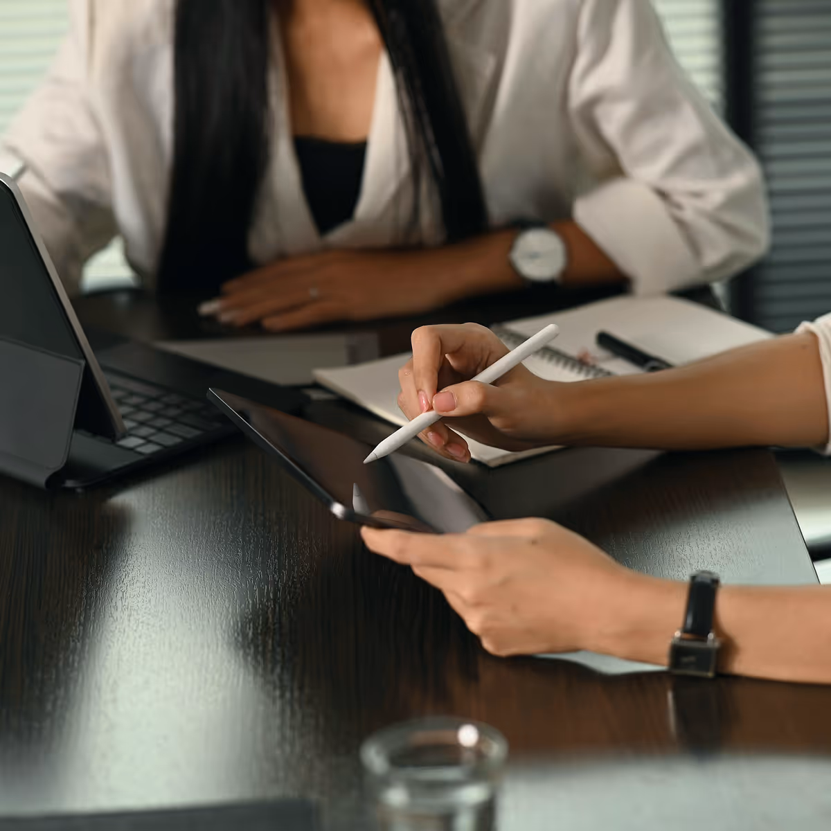 Two woman hands over papers and tablet going through consultation process.