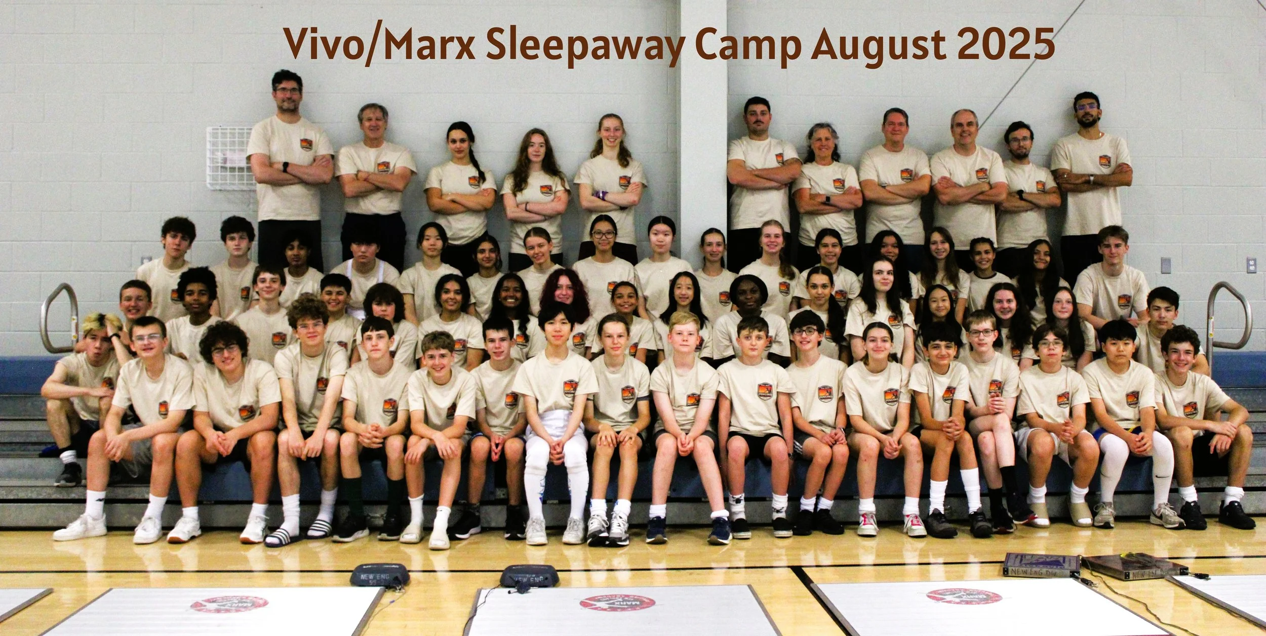 Large group photo of campers and staff in matching beige T-shirts seated and standing in a gym, titled Vivo/Marx Sleepaway Camp August 2025.