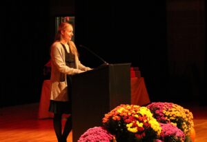 Brittany Taylor, Library director, speaking at the 2023 Nickerson Lecture in front of a podium with flowers