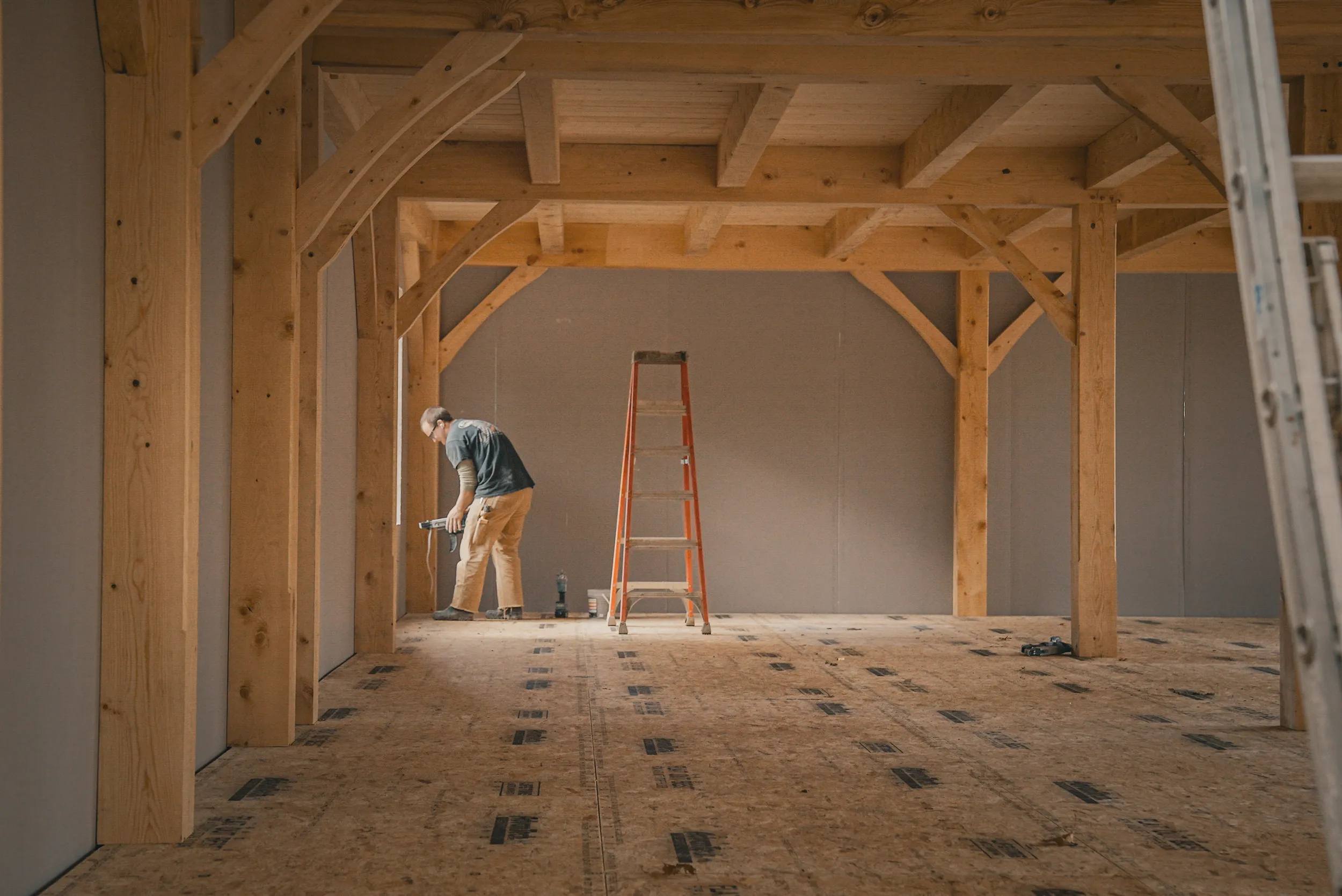 Bright wooden interior of timber frame room with large windows and trees