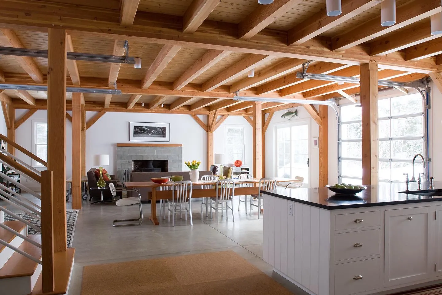 Modern open-concept barn home with exposed wood beams, kitchen, dining area, and living room.