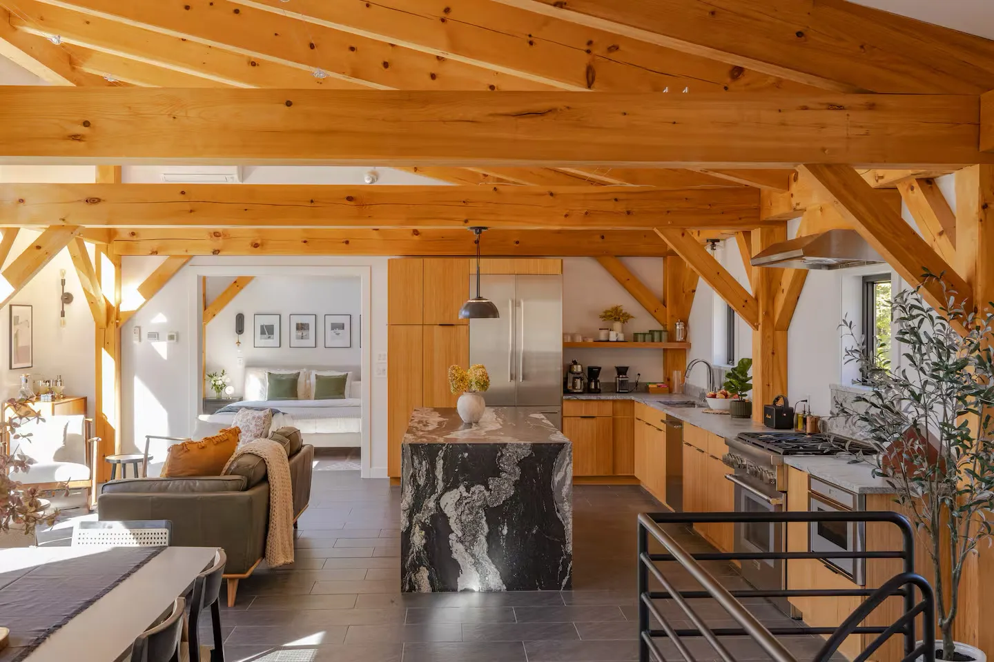 Modern farmhouse interior with exposed wooden beams, open kitchen, and living areas