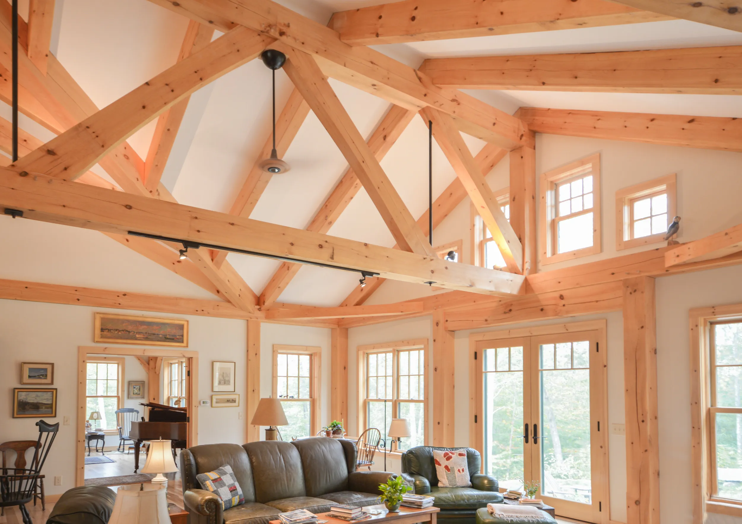 Spacious modern timber frame living room with exposed wooden beams and multiple windows.