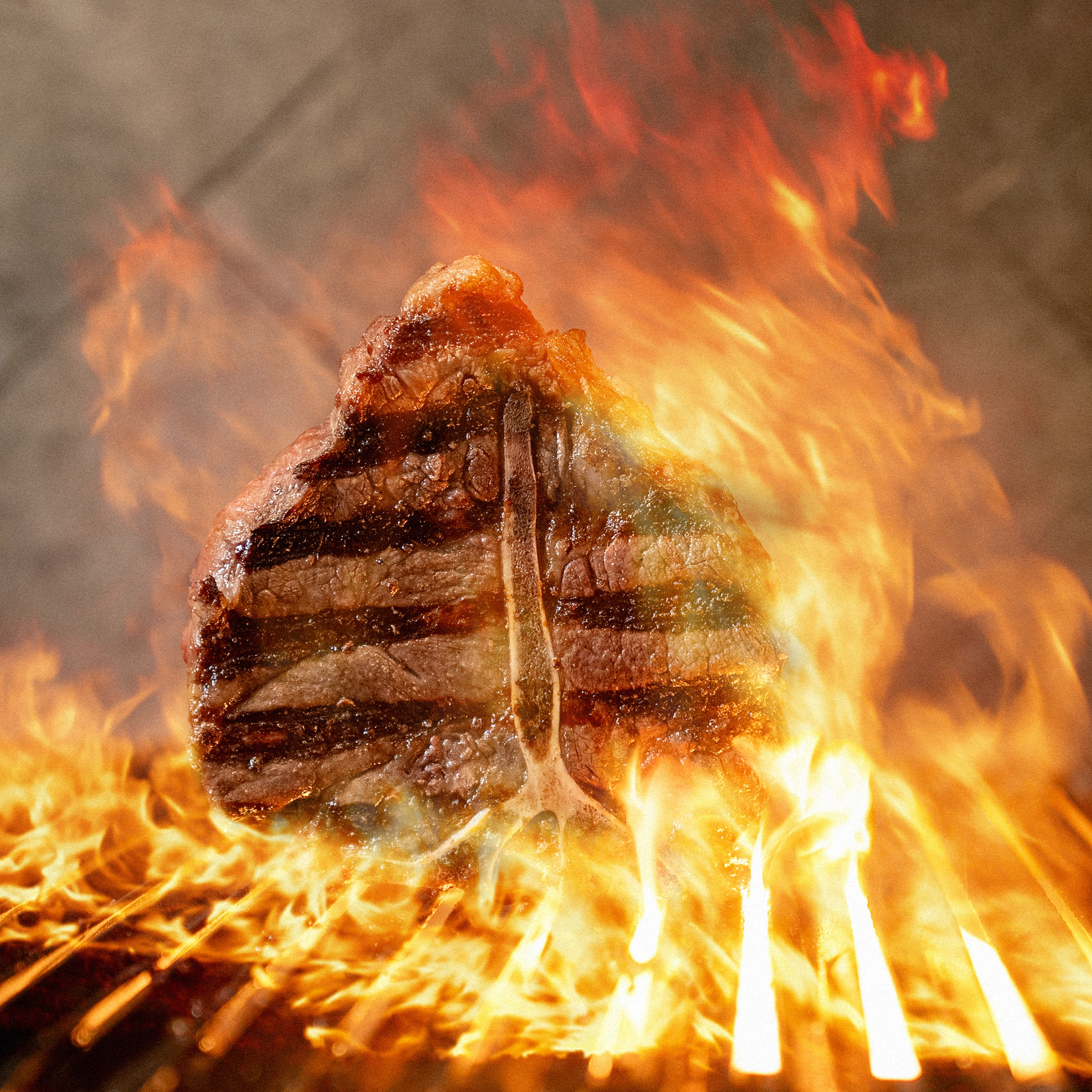 T-bone steak grilling over high flames with visible grill marks.