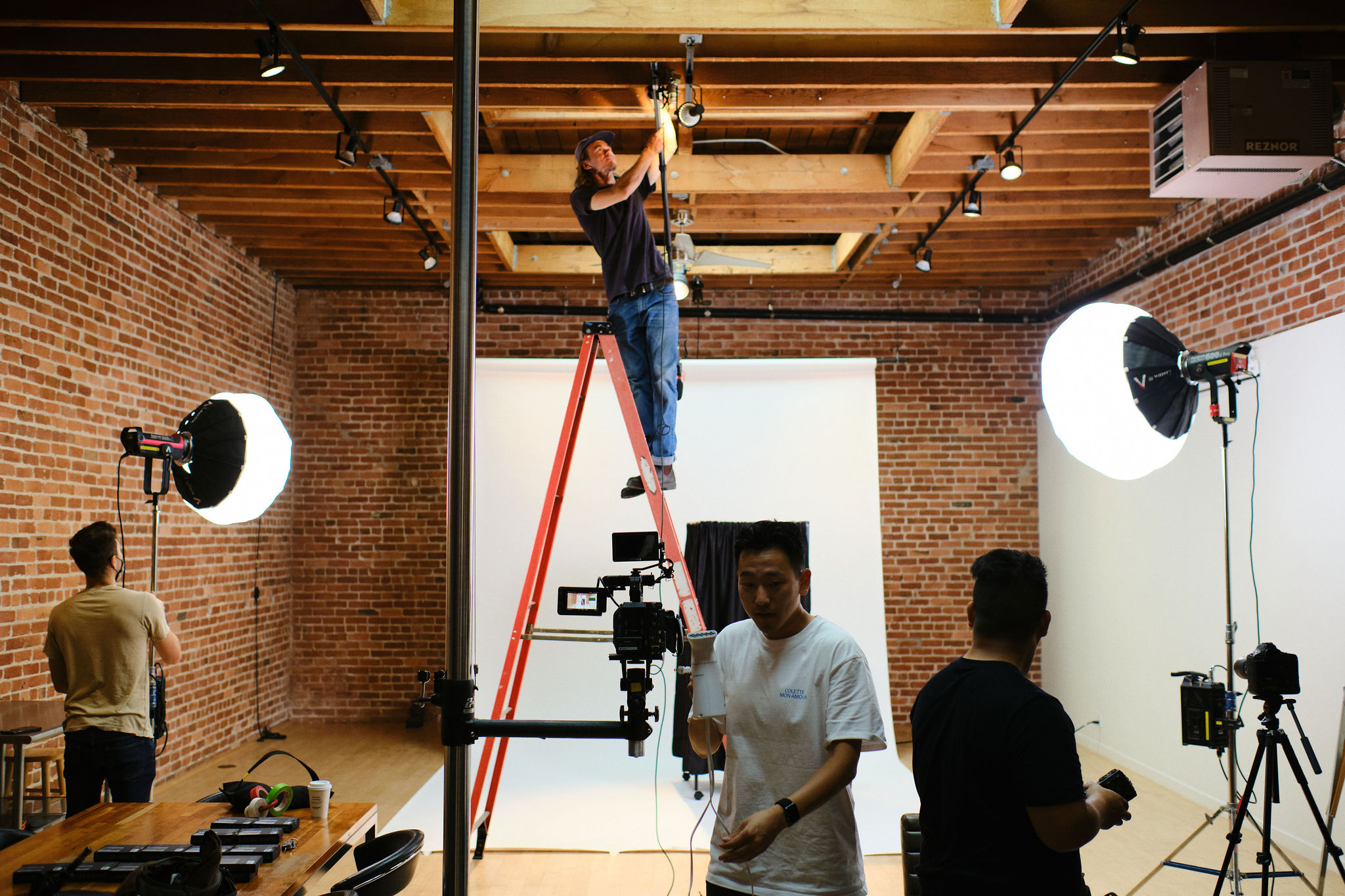 Technician hanging up lights for a video shoot stood on a ladder