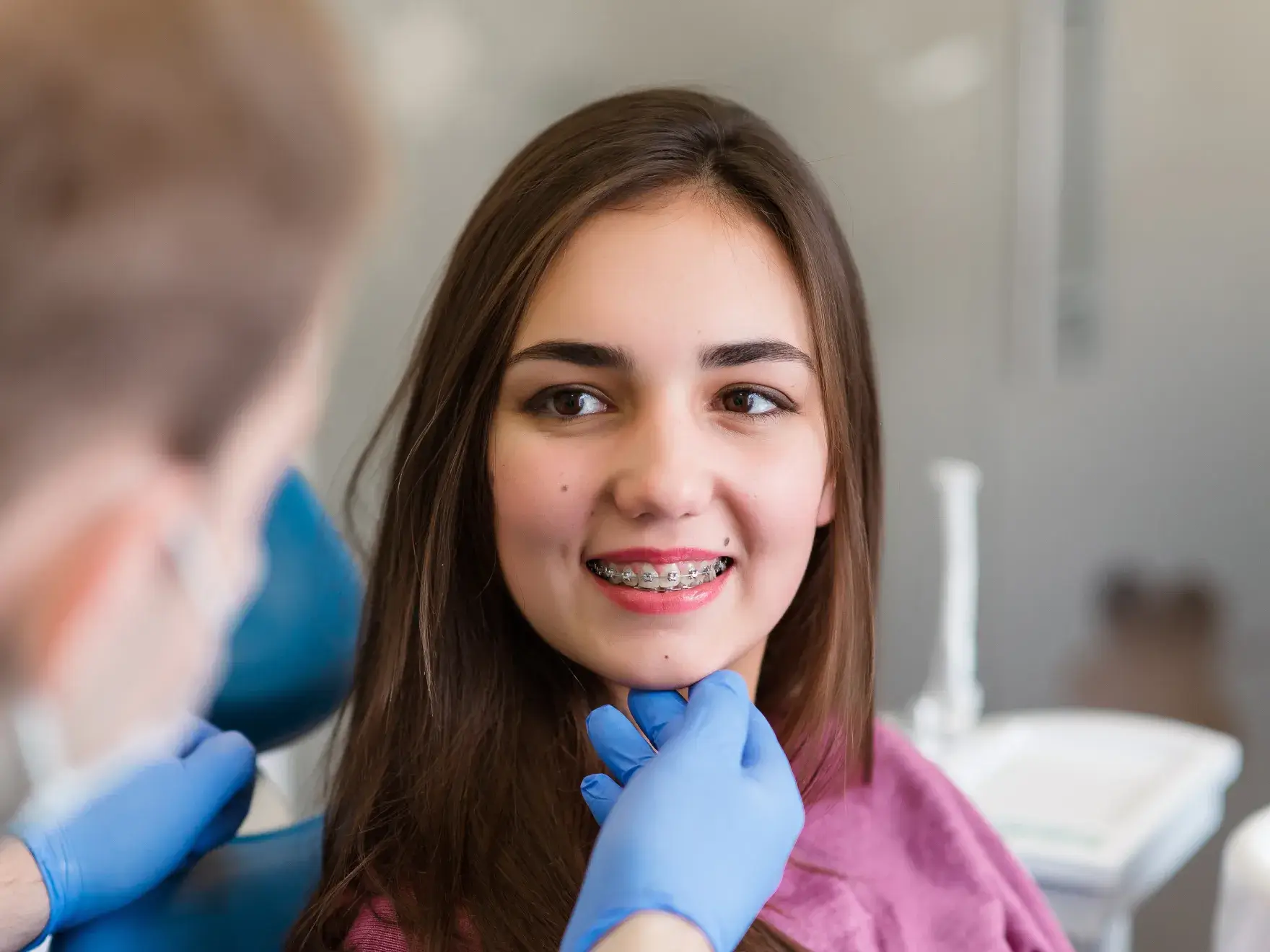 Dentist examines a smiling patient with braces during a check-up.