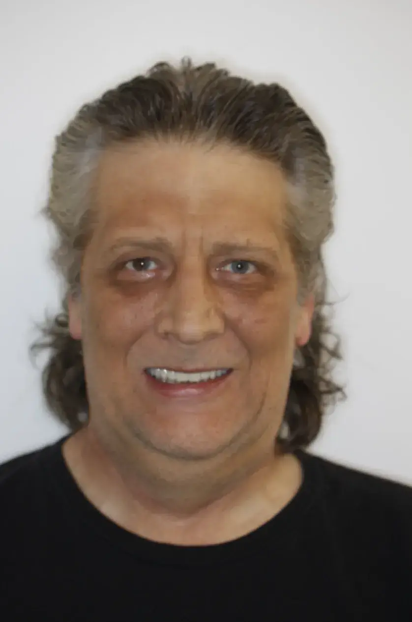 A person with long hair and a black shirt smiling at the camera.