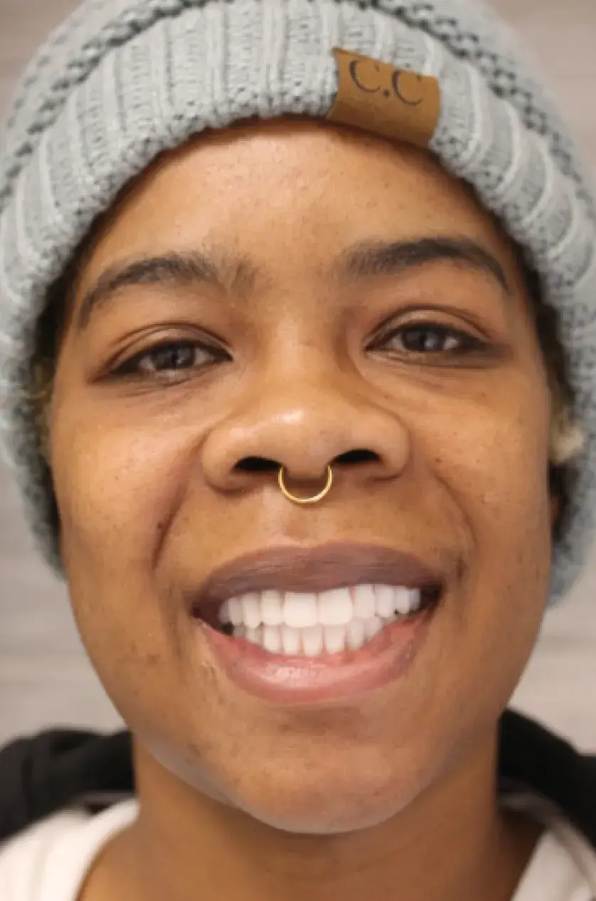 Person smiling, wearing a gray knit beanie and a nose ring.