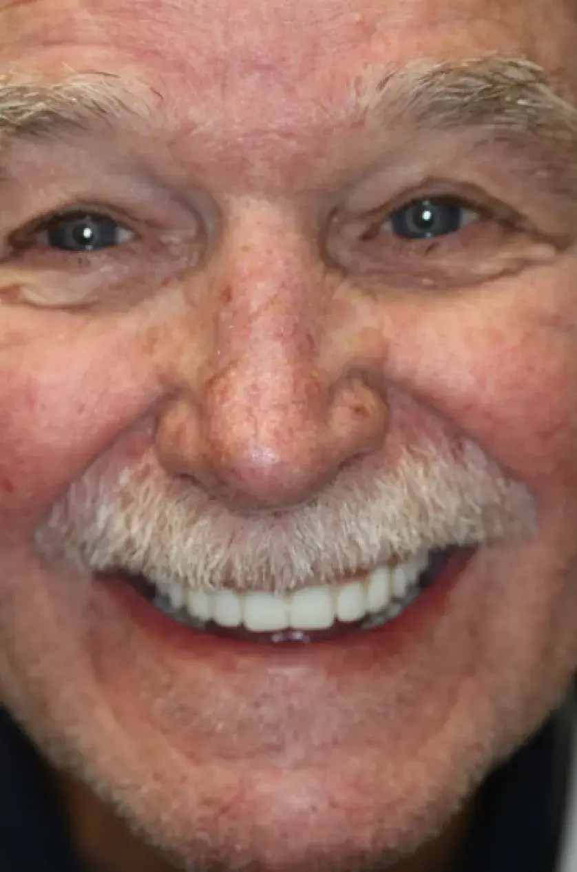 A smiling older man with a white mustache looking directly at the camera.