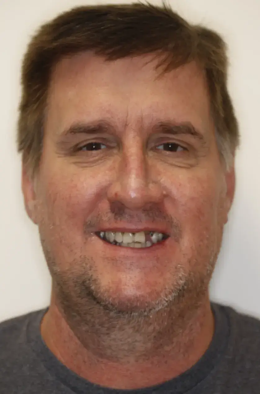 A man with short brown hair and a light beard smiles at the camera.