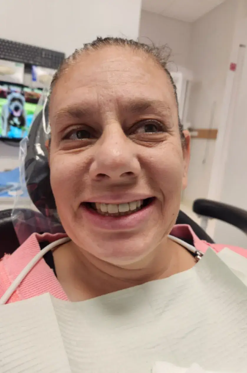 A person sitting in a dental chair, smiling, wearing a dental bib.