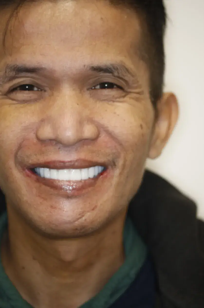 A person smiling broadly against a plain background.