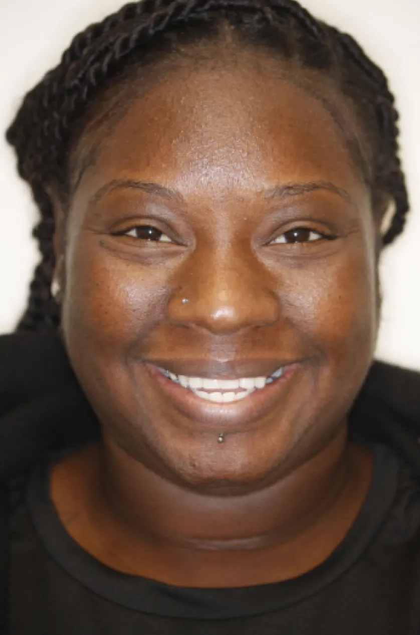 A person with braided hair smiling at the camera.