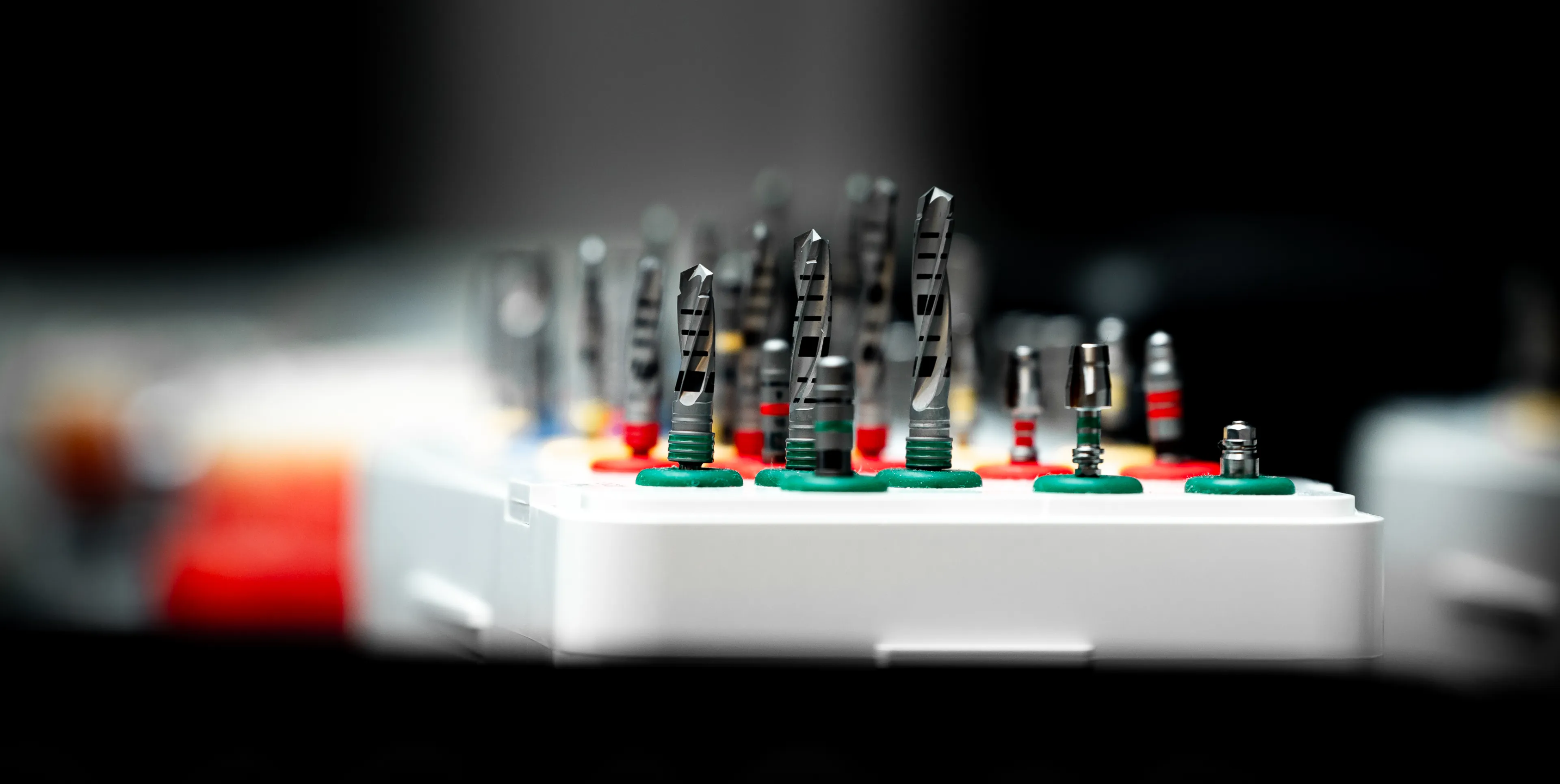 A set of colorful dental drills organized in a white holder, ready for use.