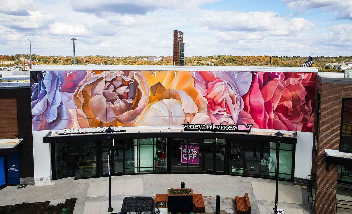 Storefront with a large colorful mural of close-up rose flowers in various shades of purple, yellow, orange, pink, and red above the entrance.