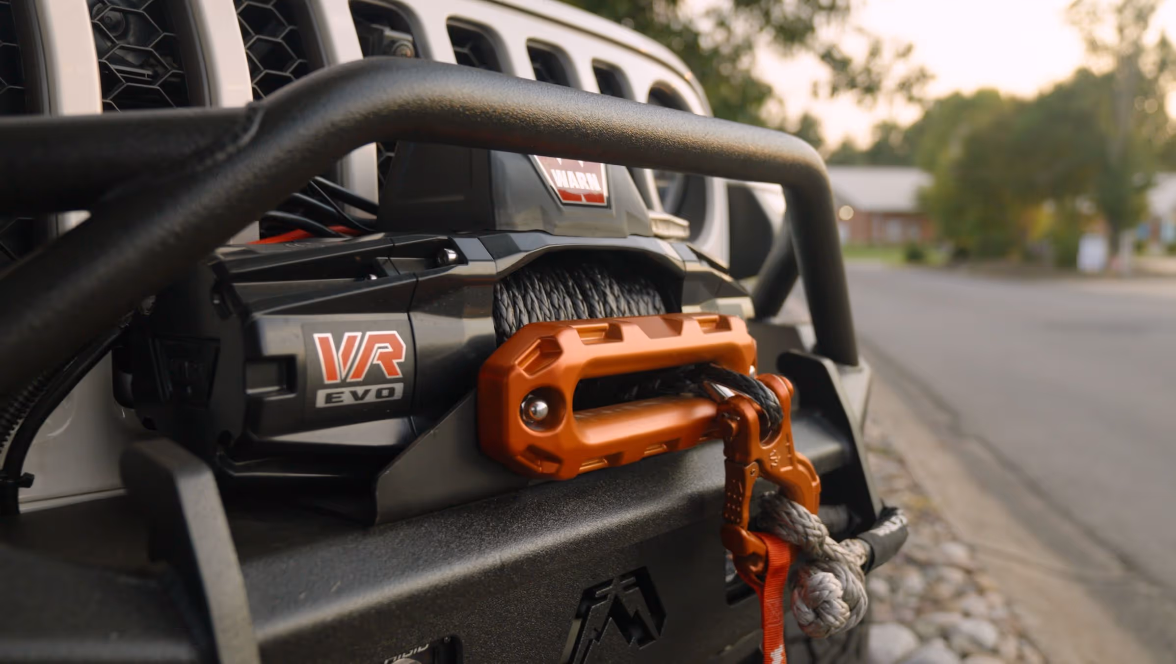 Close-up of a VR EVO winch with an orange hook mounted on the front bumper of an off-road vehicle.