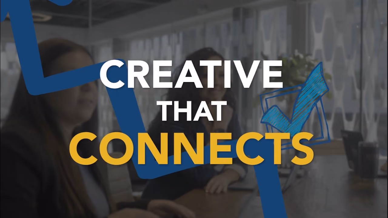Two women sitting at a table in a modern office with overlaid text saying 'CREATIVE THAT CONNECTS' and graphical blue checkmarks.
