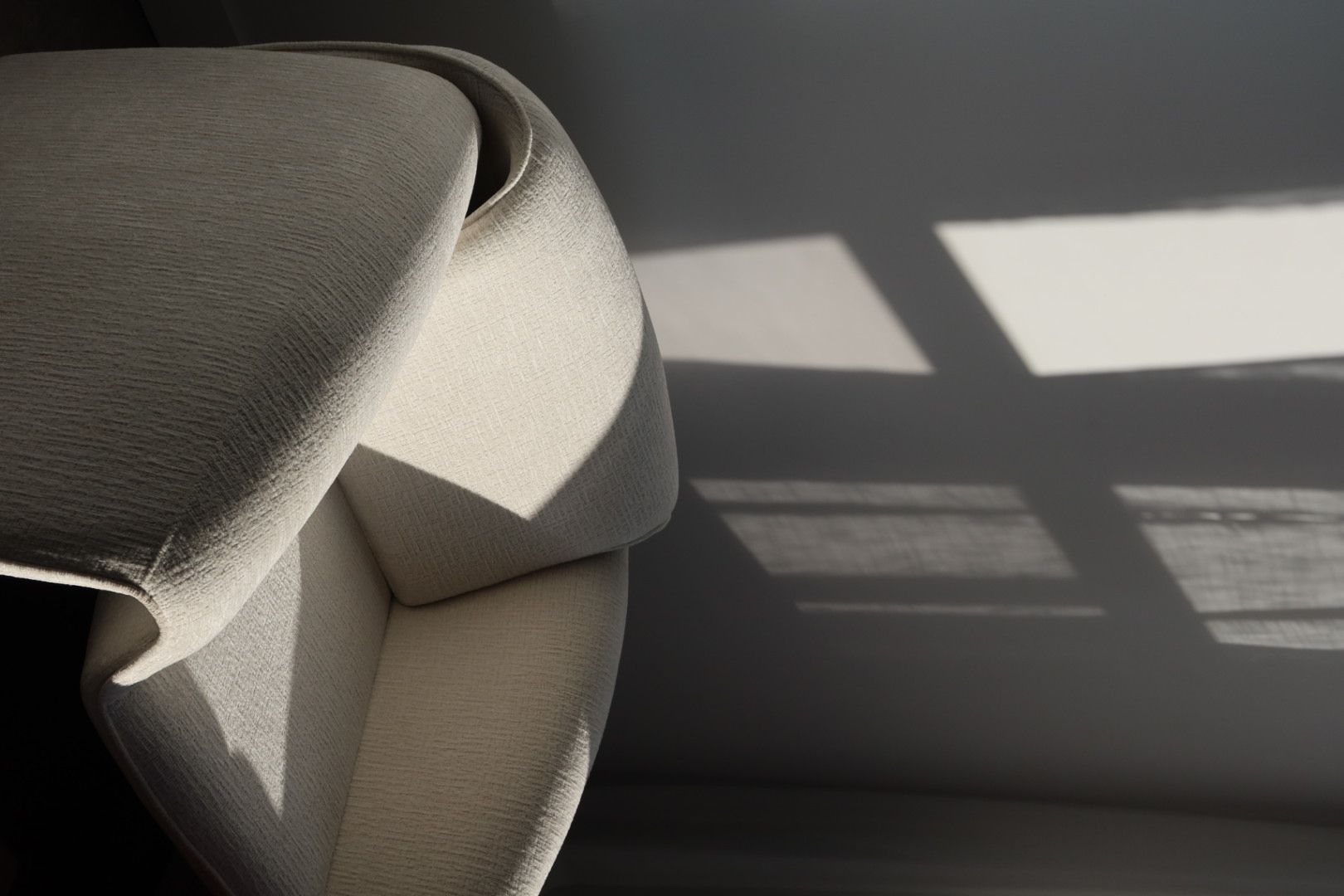 Living room with a rust-colored plush sofa, modern beige coffee table with books and a black vase, a wooden chair with woven seat, and sheer white curtains.