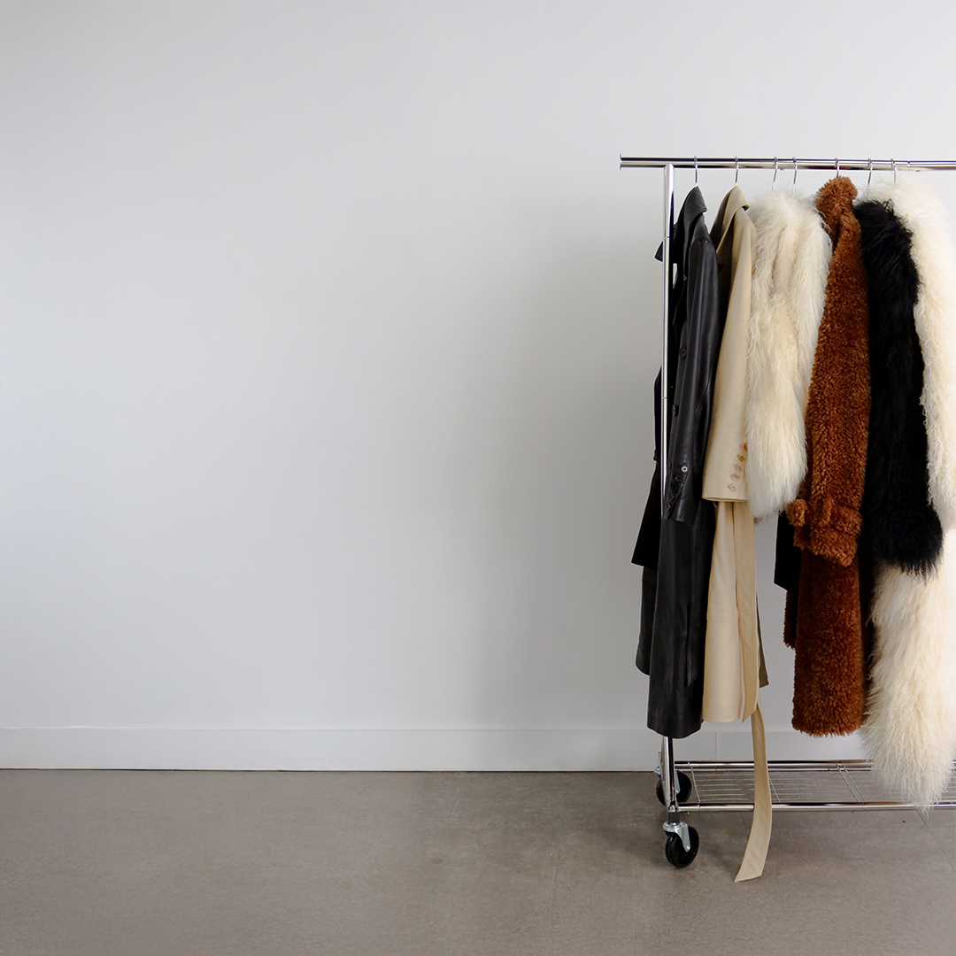 White curvy coffee table with a black Chanel book and a small black vase on top, next to an orange couch on a textured beige carpet.