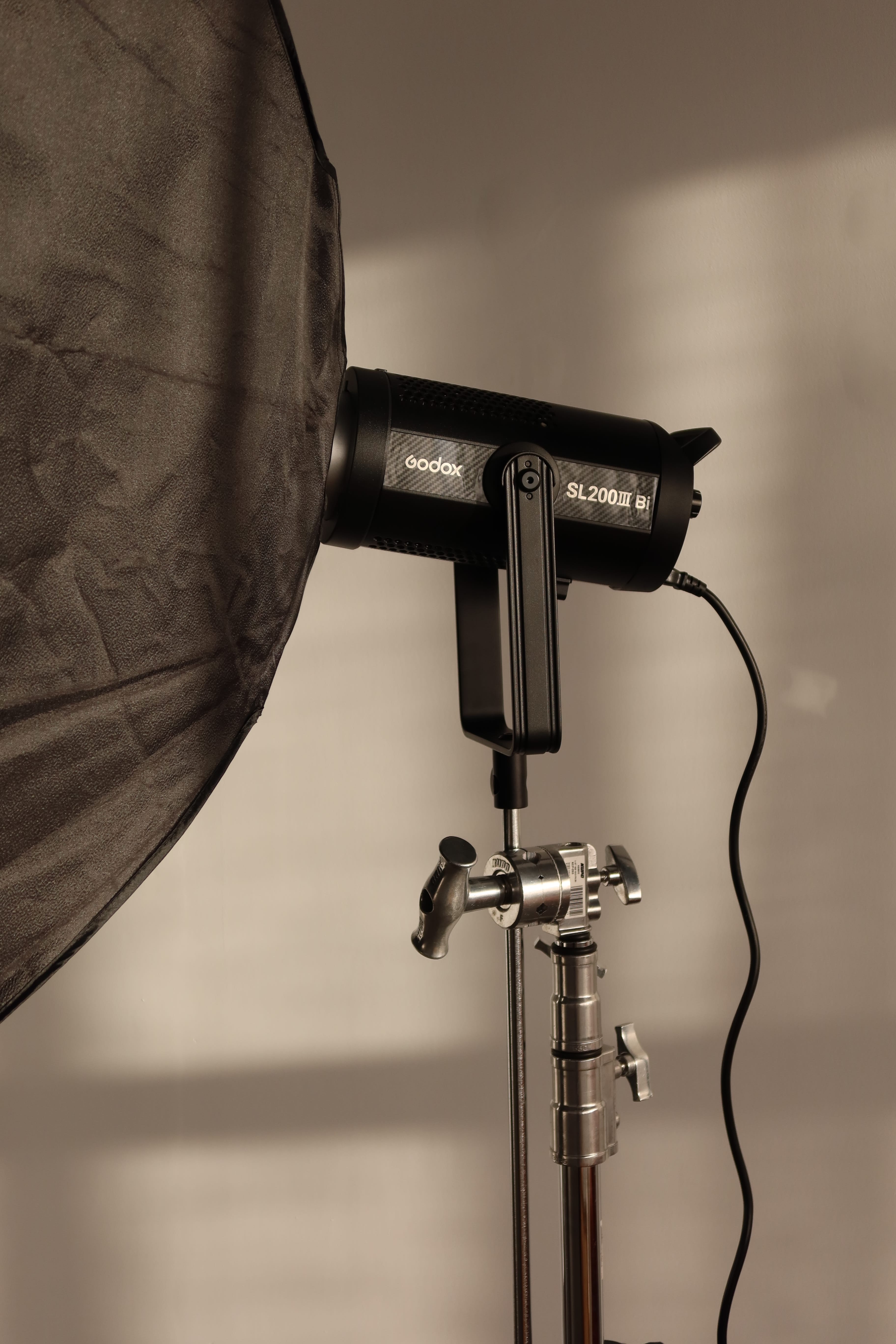 Living room with a rust-colored plush sofa, modern beige coffee table with books and a black vase, a wooden chair with woven seat, and sheer white curtains.